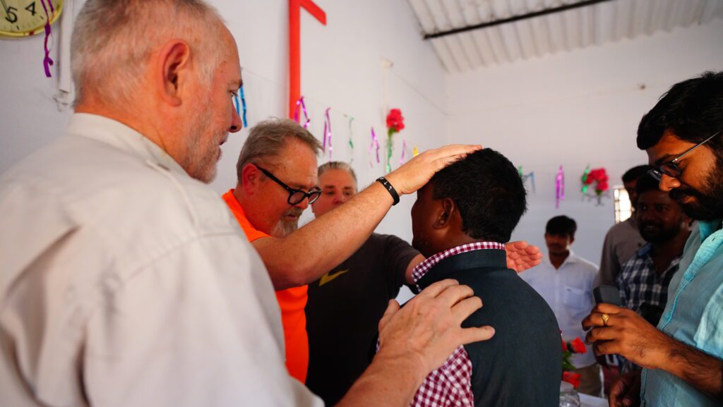 A young man being prayed over by three missionaries.
